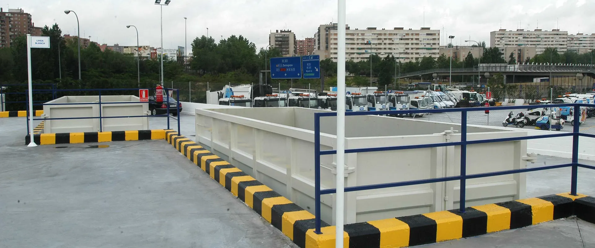 Contenedores abiertos del punto limpio fijo de Hortaleza, con bloques de viviendas al fondo