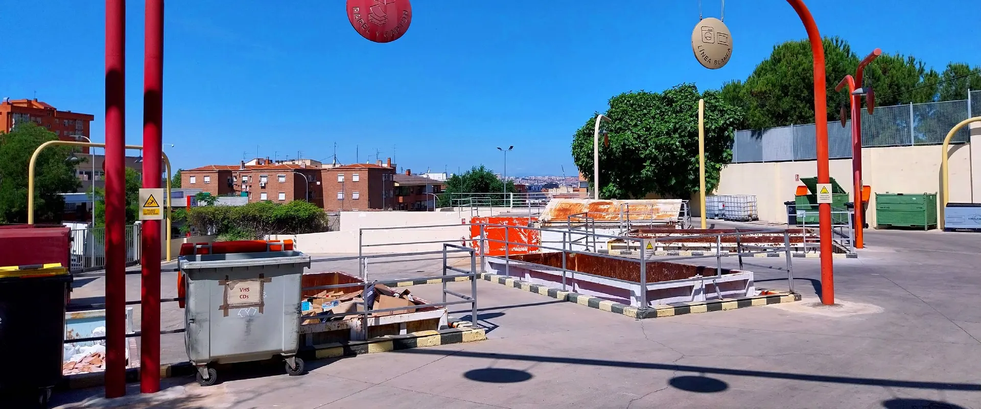 Contenedores y pórticos rojos del punto limpio fijo de Puente de Vallecas bajo un cielo despejado